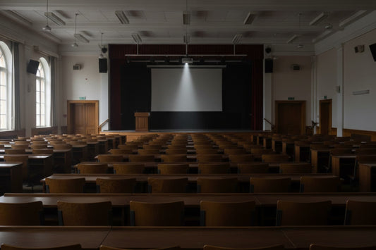 Empty university lecture hall with rows of wooden seats and a lit projection screen, representing faculty attrition in higher education